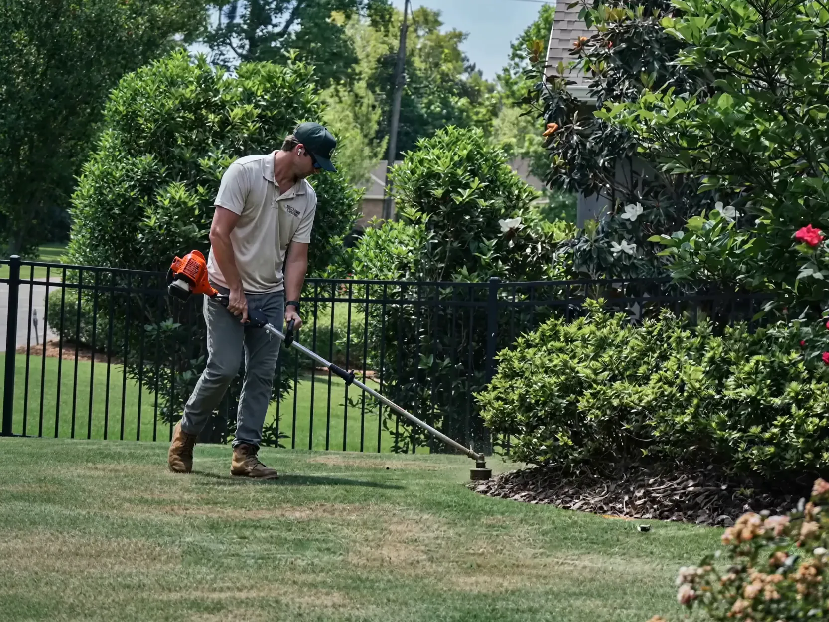 Rolling Lawns crew member edging a lawn beside a fence in Auburn, Alabama