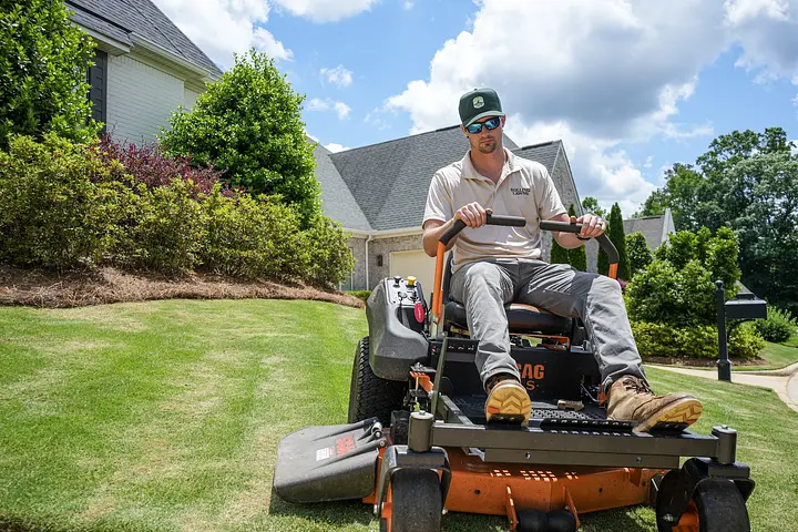 Rolling Lawns owner riding a Scag zero-turn mower across a front lawn